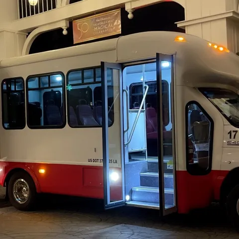 A red and white shuttle bus with open doors and a wheelchair lift at night.