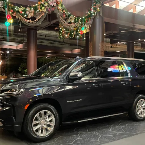 Black SUV parked indoors with festive decorations overhead.