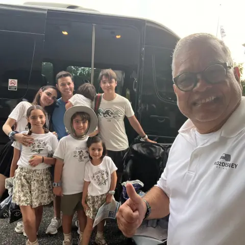 Smiling group in front of a van, one person gives a thumbs up.