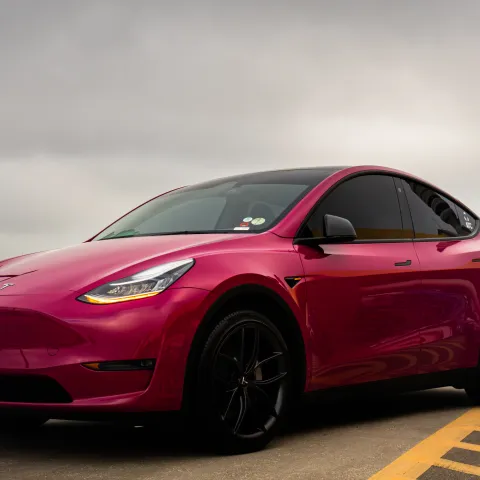 Red electric car parked in a lot on a cloudy day.