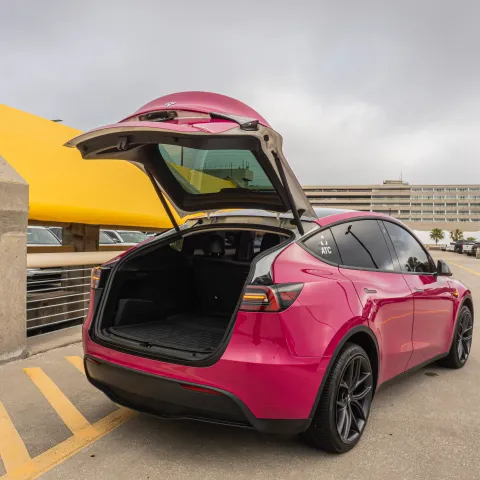 Red electric SUV with open trunk in a parking structure.